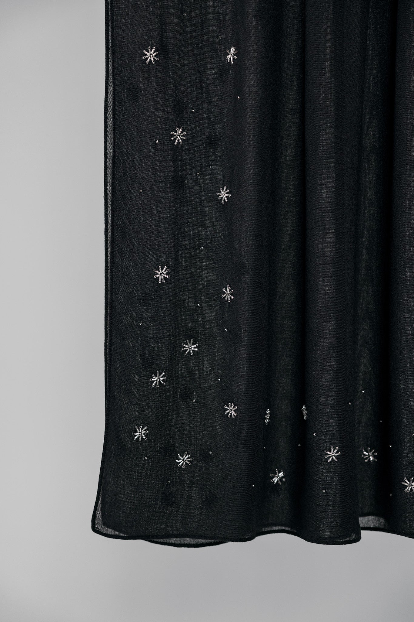 Black fabric with silver star-like embellishments on a plain background