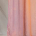 Pink, orange, purple gradient hijab draped in front of a neutral background
