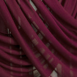 Maroon hijab suspended and gently draped to show the lightweight fabric and texture in soft lighting.