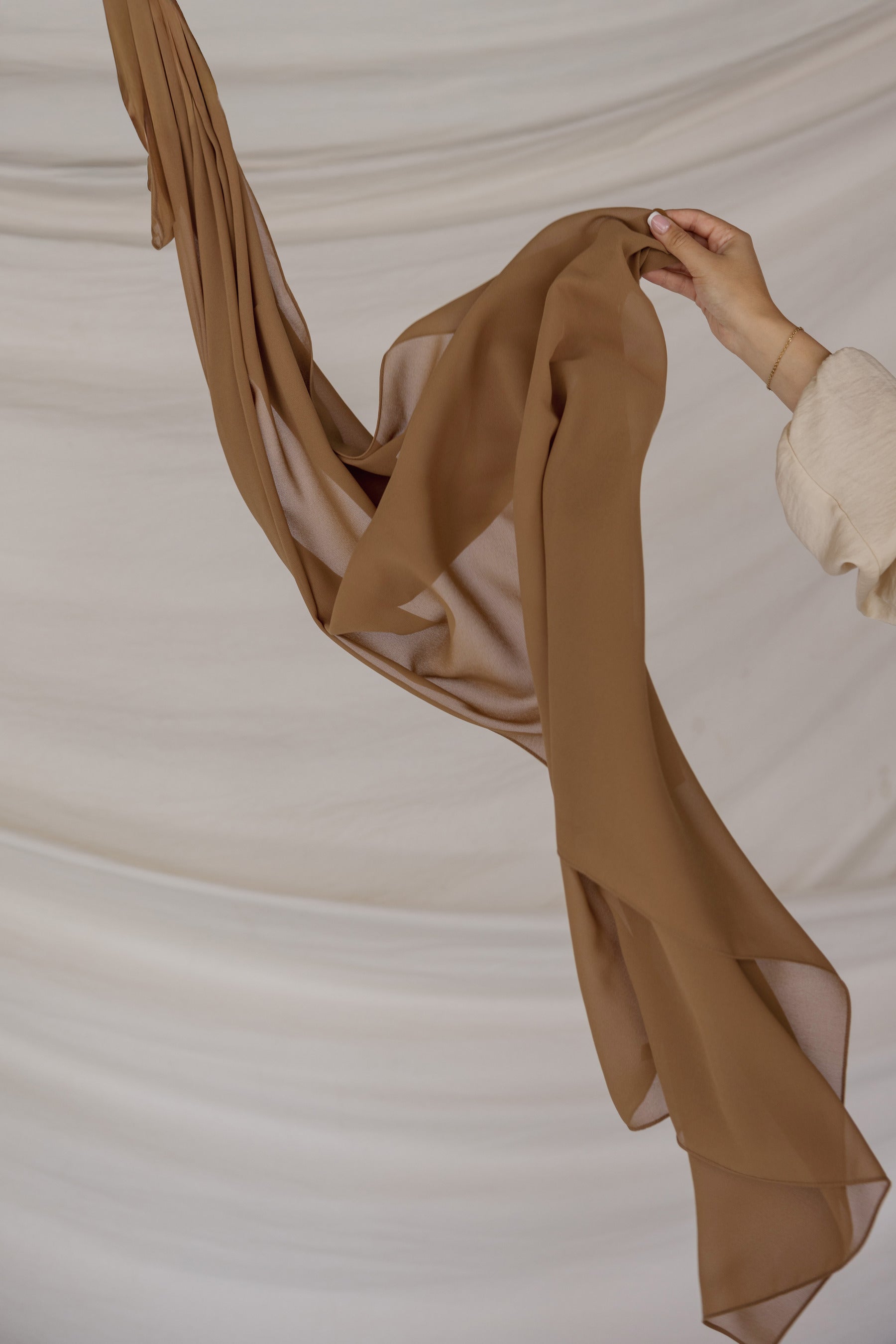 Brown fabric being held against a neutral background