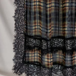 Plaid fabric with black lace trim on a neutral background