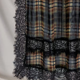 Plaid fabric with black lace trim on a neutral background
