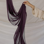 Purple hijab being held against a neutral background