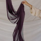 Purple hijab being held against a neutral background