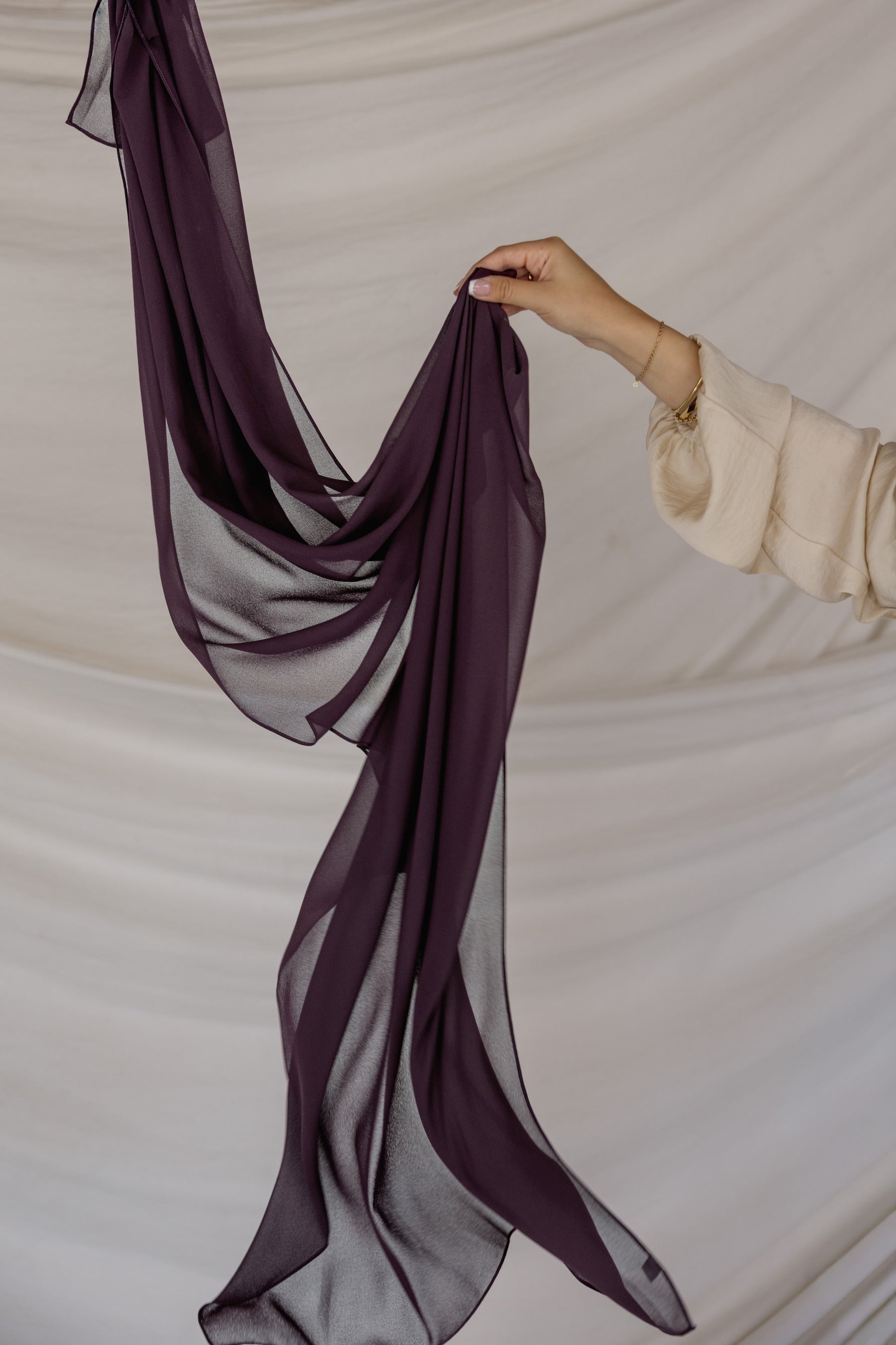 Purple hijab being held against a neutral background