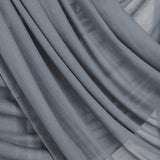 Close-up of draping folds of the dark sage hijab over a neutral backdrop.
