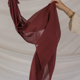 Red chiffon hijab being held against a beige background
