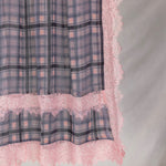 Plaid fabric with pink lace trim on a gray background