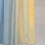 Close up of yellow to blue ombre hijab draped in front of white background