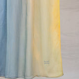 Close up of yellow to blue ombre hijab draped in front of white background