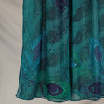 Teal fabric with peacock feather pattern on a beige background