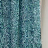 A close-up product shot of the Aqua Cobra scarf that features blue and teal scale-like designs.