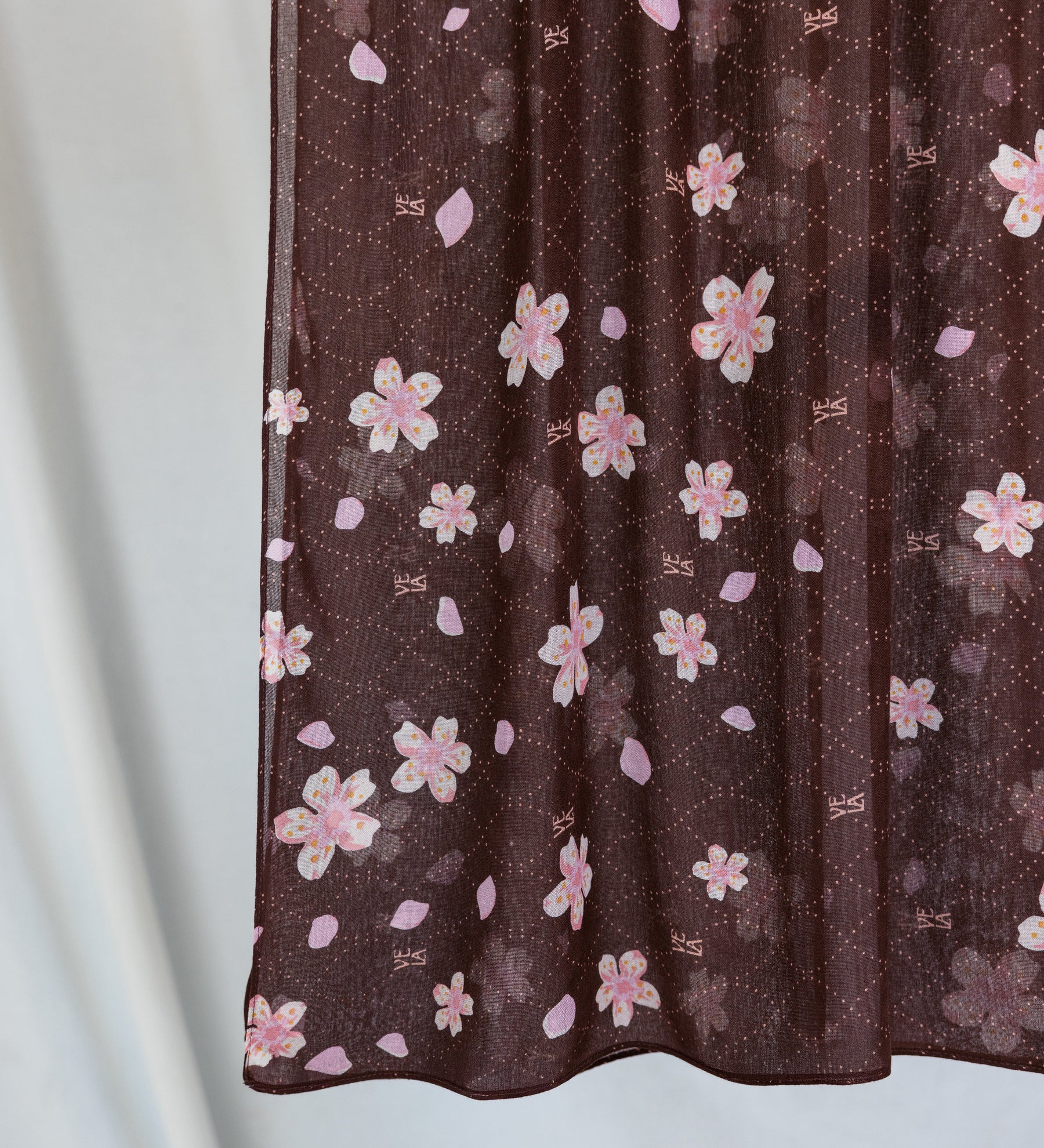 A product image showing a brown hijab printed with pink and white cherry blossoms. 