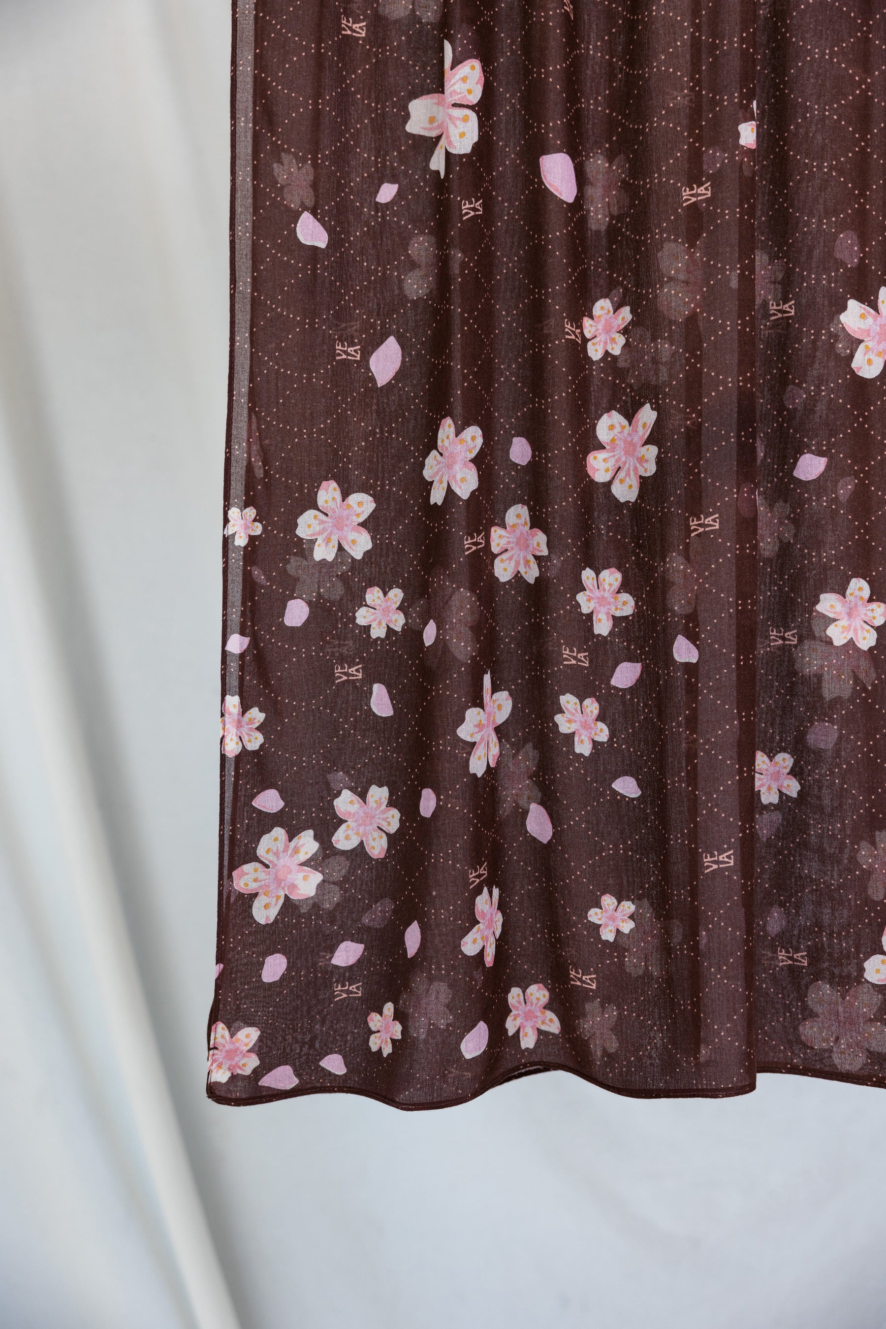 A product image showing a brown hijab printed with pink and white cherry blossoms. 