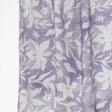 A close-up of a lavender and white floral patterned fabric, likely a scarf or lightweight wrap, shown hanging against a plain white background.