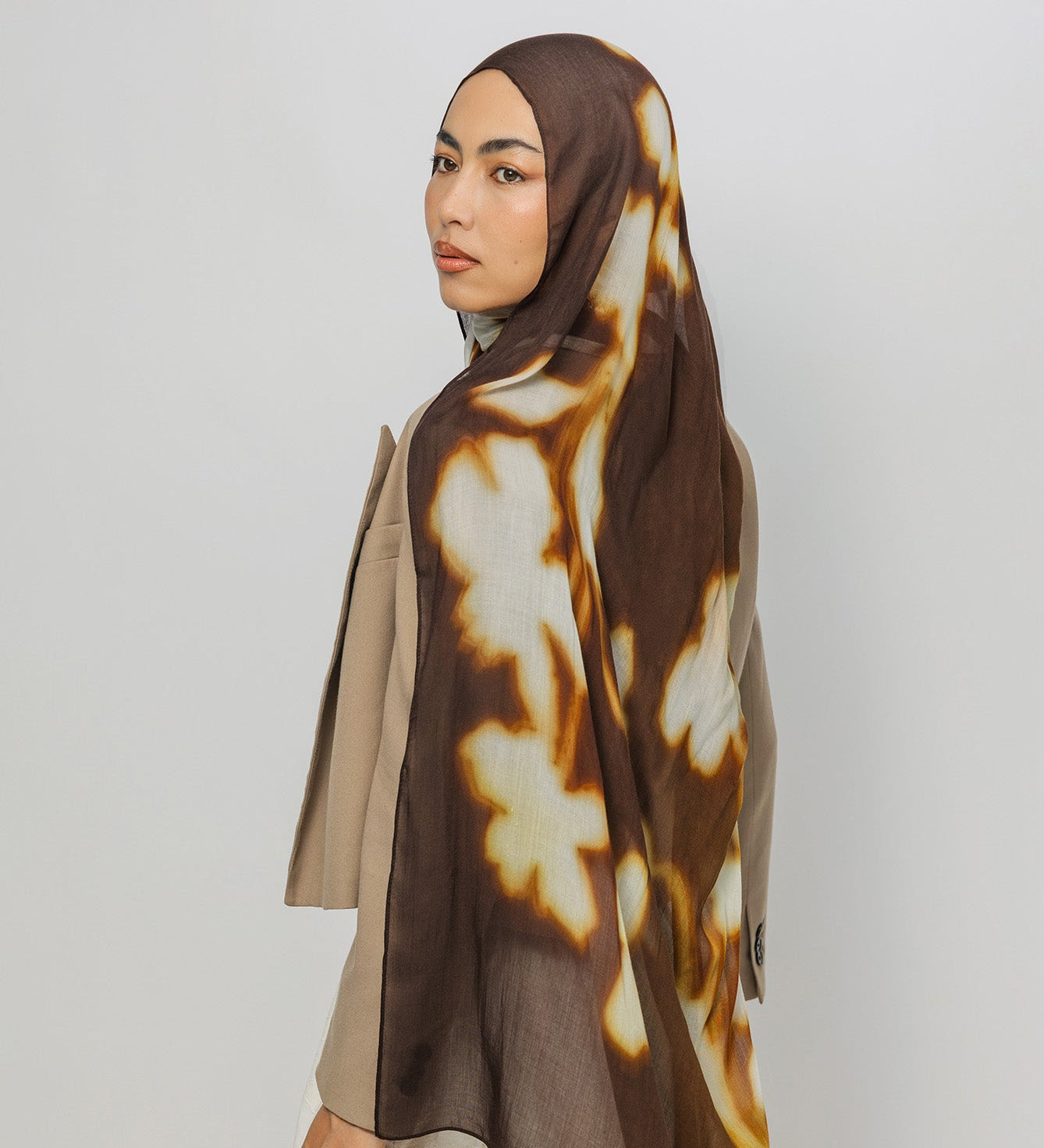 Woman wearing a brown and beige patterned hijab on a white background