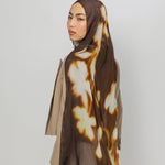 Woman wearing a brown and beige patterned hijab on a white background