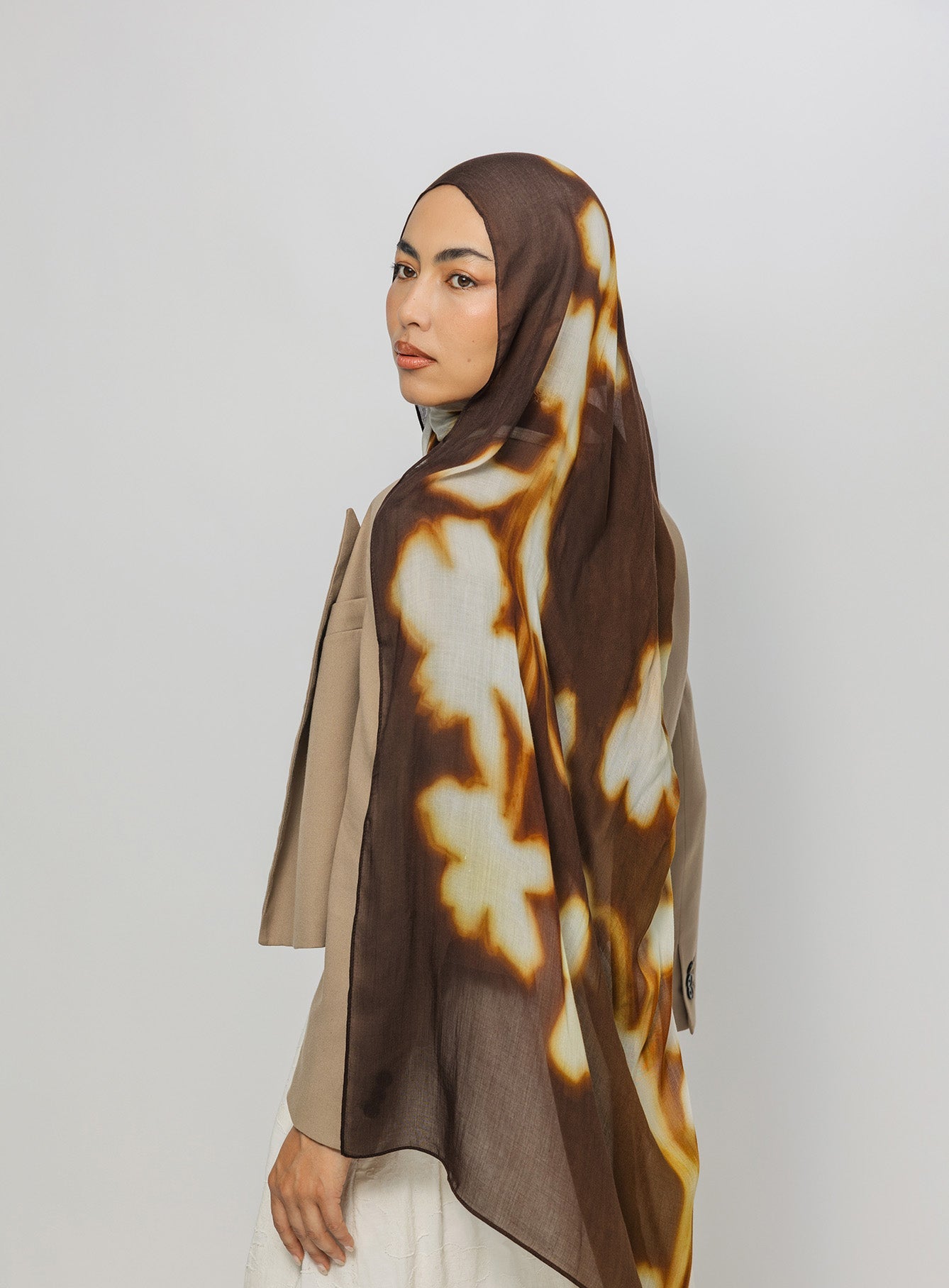 Woman wearing a brown and beige patterned hijab on a white background