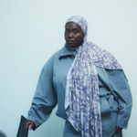 A woman wearing a light purple and white patterned hijab in a soft blue track suit. 