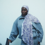 A woman wearing a light purple and white patterned hijab in a soft blue track suit. 