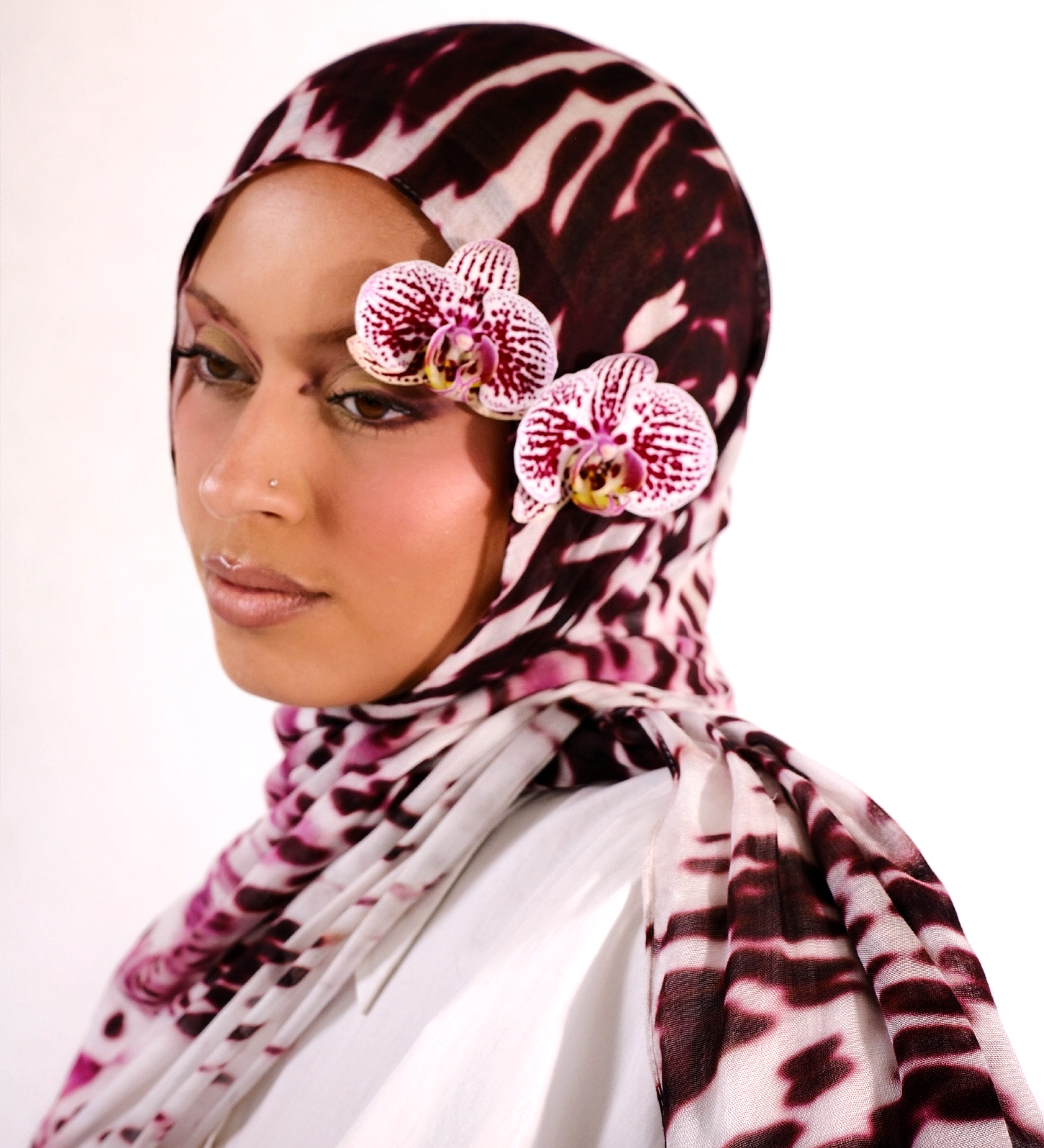 Woman wearing a patterned hijab with pink flowers on a white background