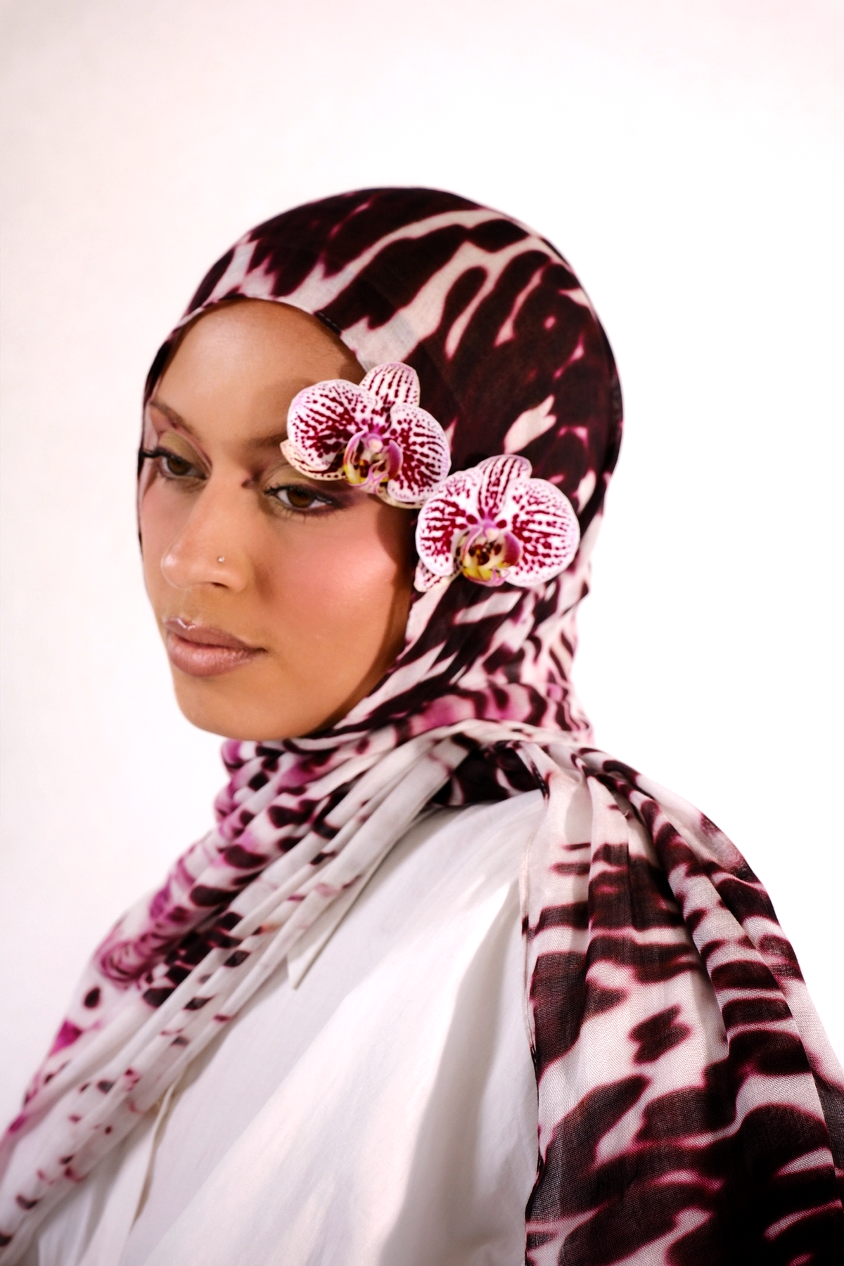 Woman wearing a patterned hijab with pink flowers on a white background