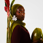 Woman holding a papaya with a red flower and green leaves on a white background