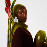 Woman holding a papaya with a red flower and green leaves on a white background