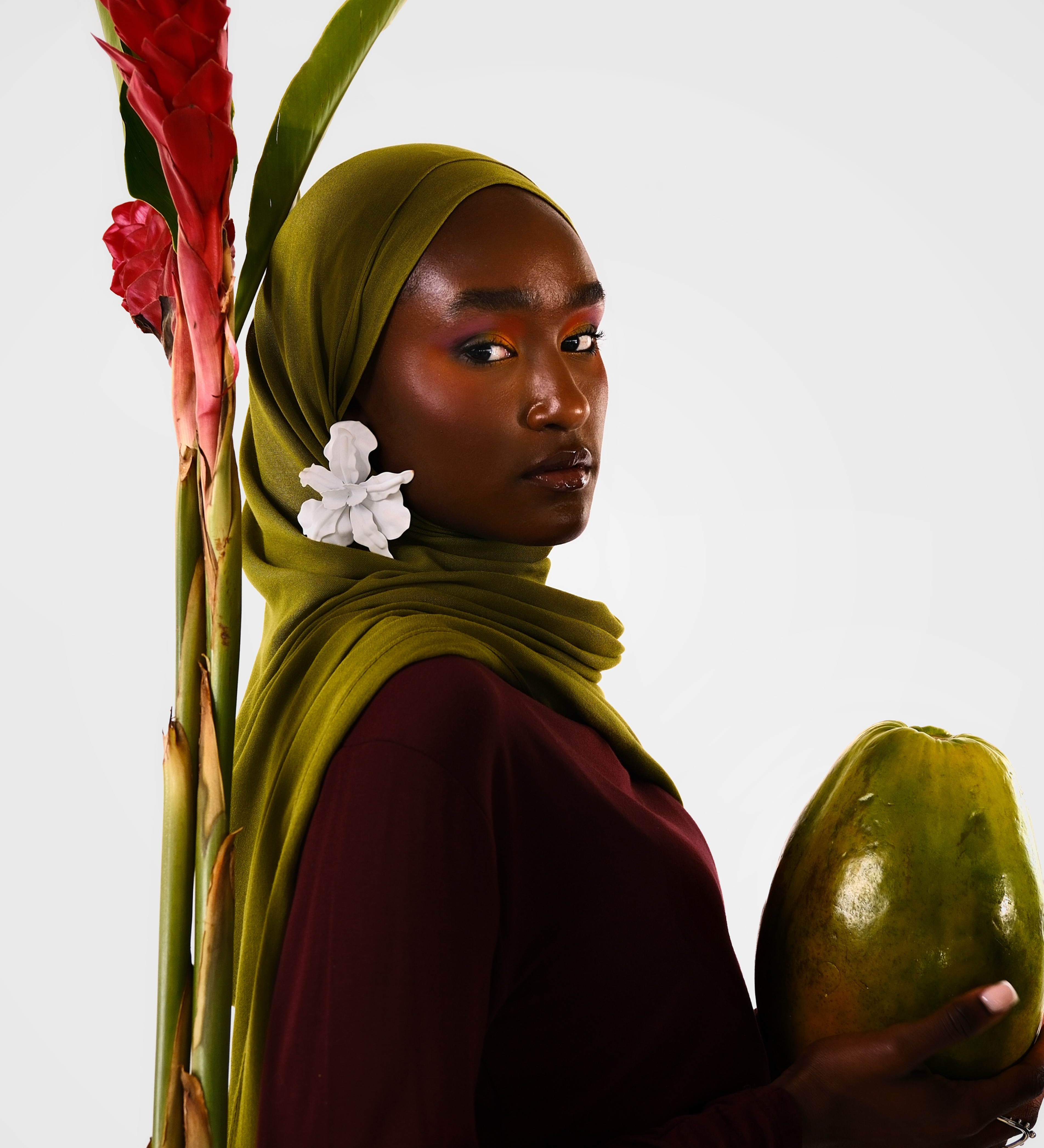 Woman holding a papaya with a red flower and green leaves on a white background
