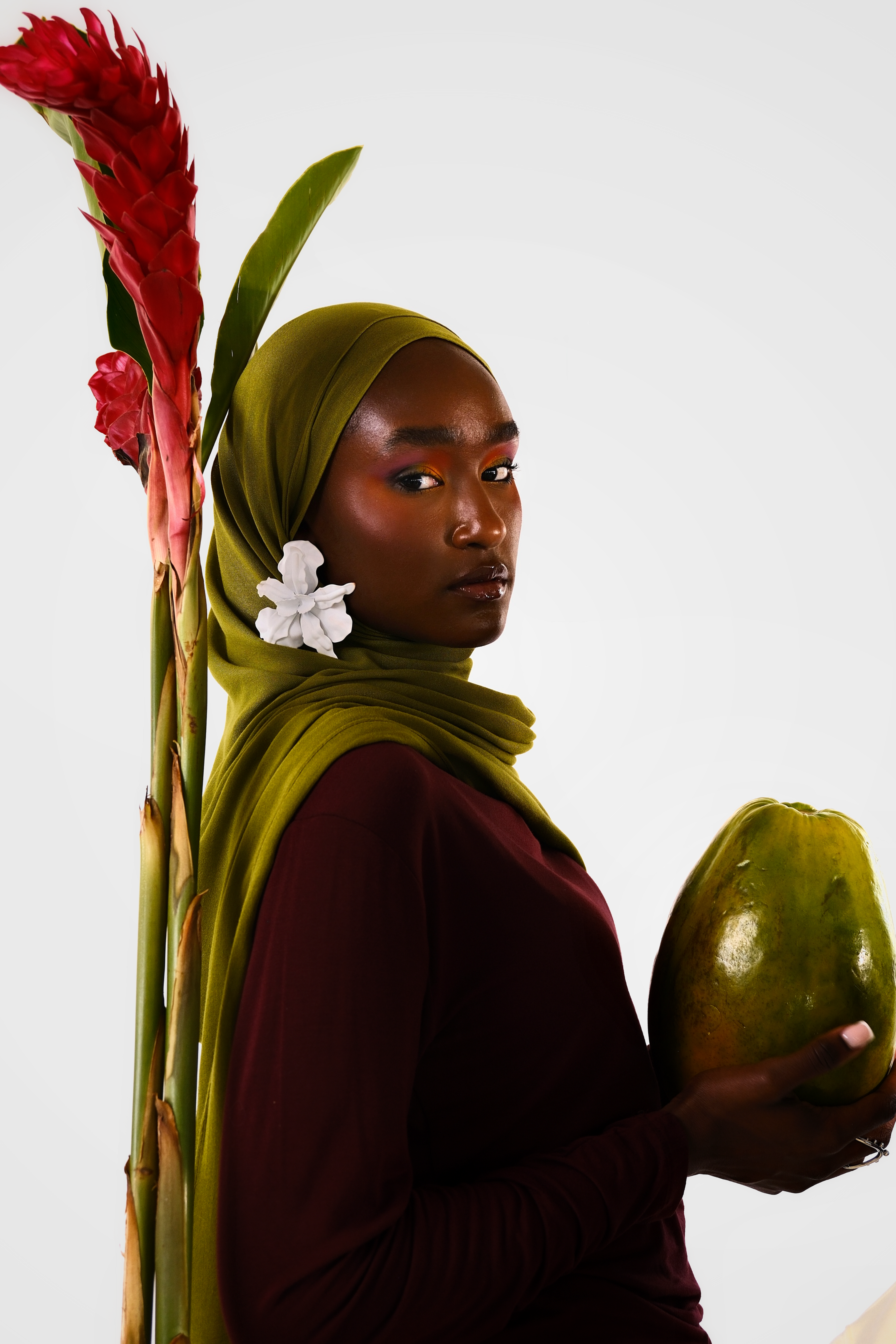 Woman holding a papaya with a red flower and green leaves on a white background