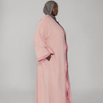 Woman wearing a pink abaya with a gray hijab on a white background