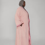 Woman wearing a pink abaya with a gray hijab on a white background