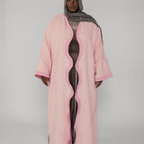 Person wearing a pink abaya with a gray hijab on a white background