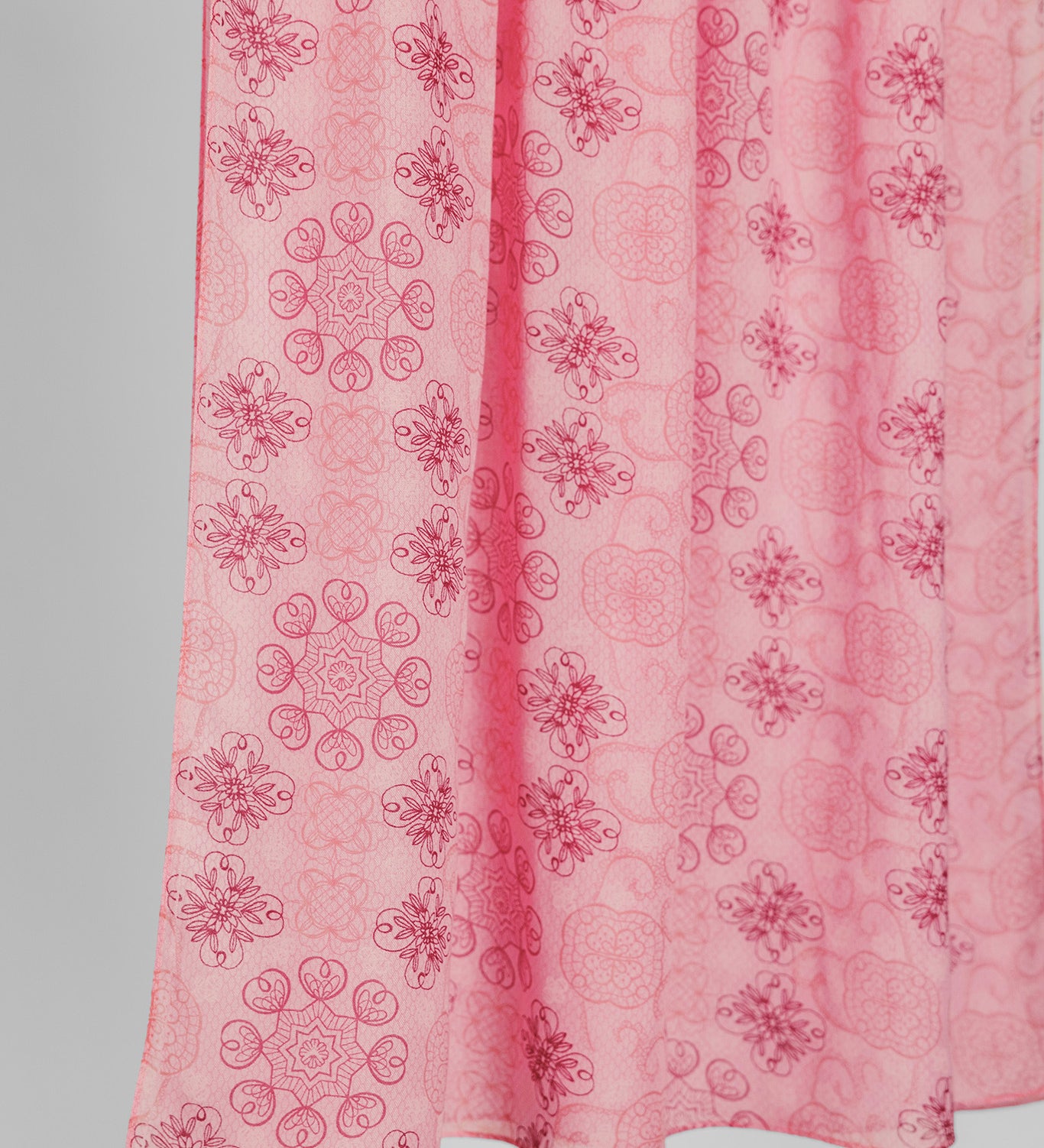 Pink hijab fabric with floral pattern on a plain background