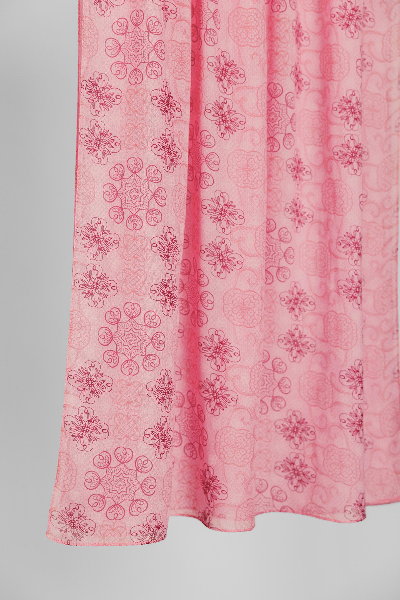Pink hijab fabric with floral pattern on a plain background