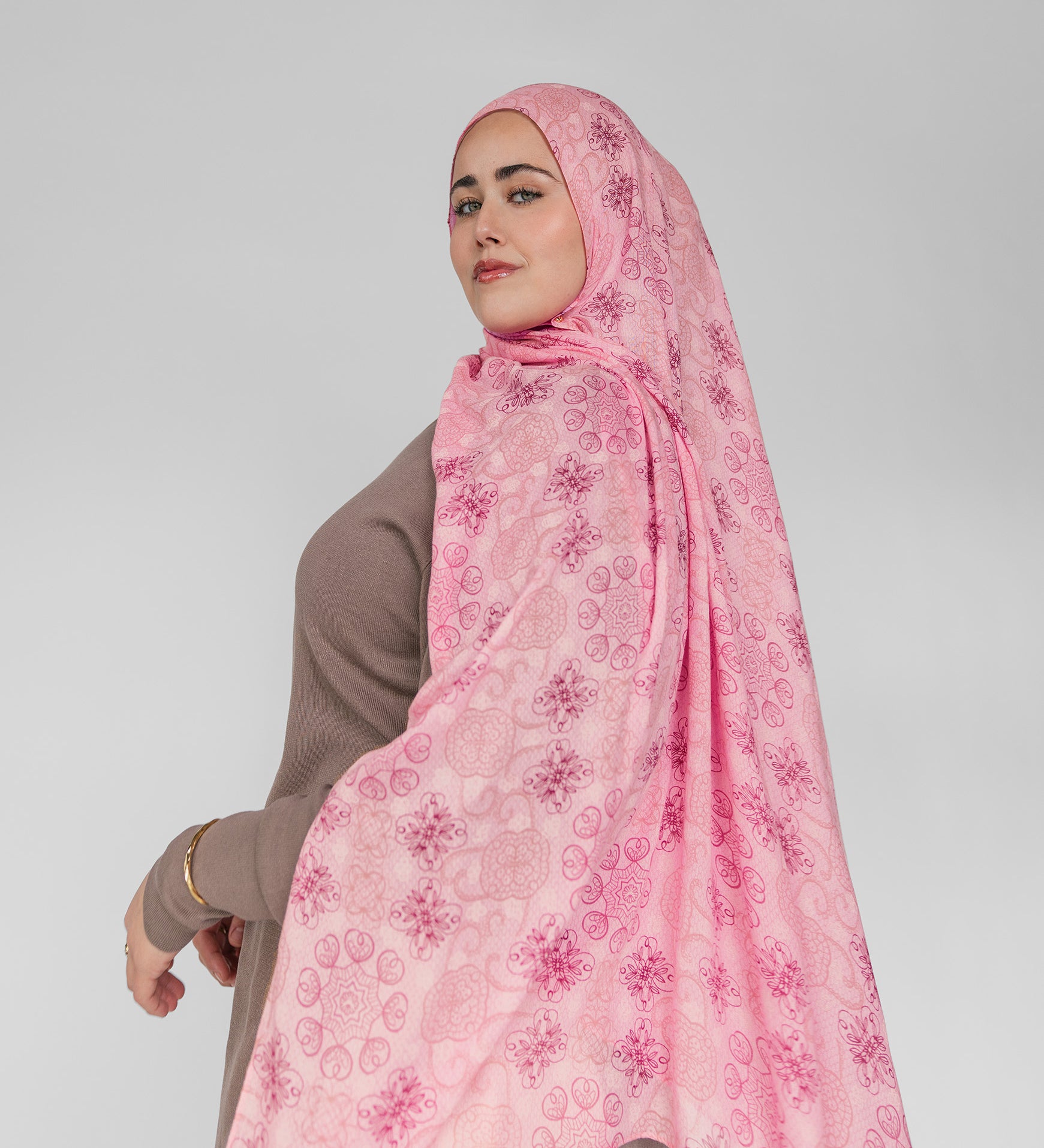 Woman wearing a pink floral hijab on a white background