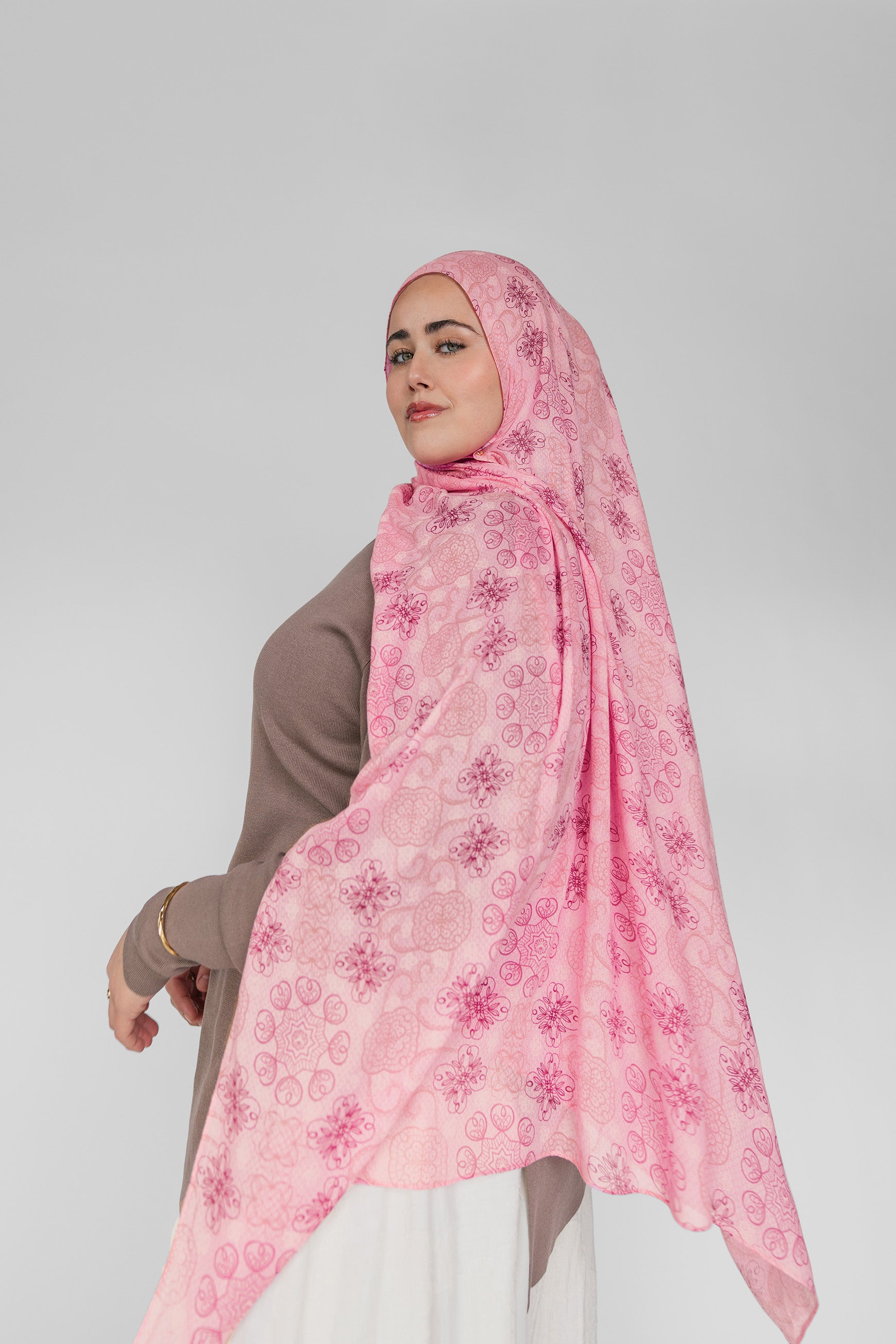 Woman wearing a pink floral hijab on a white background