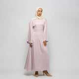 Woman wearing a light pink dress and hijab on a white background