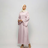 Woman wearing a light pink dress and hijab on a white background