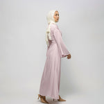 Woman wearing a light pink dress and hijab on a white background