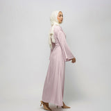 Woman wearing a light pink dress and hijab on a white background