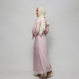 Woman wearing a light pink dress and beige hijab against a white background