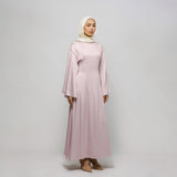 Woman wearing a long pink dress and hijab on a white background