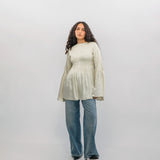 Woman wearing a light-colored blouse and blue jeans against a white background
