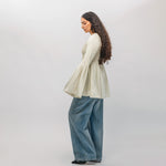 Woman wearing a light-colored sweater and blue jeans on a white background