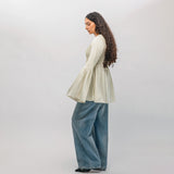Woman wearing a light-colored sweater and blue jeans on a white background