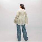Person wearing a light-colored blouse and blue jeans against a white background