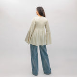 Person wearing a light-colored blouse and blue jeans against a white background