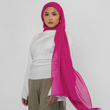 Person wearing a white top and beige pants with a pink hijab on a white background