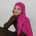 Person wearing a bright pink hijab and brown outfit on a plain background